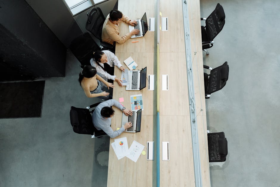 High angle view of colleagues working together on laptops in a modern office setting.